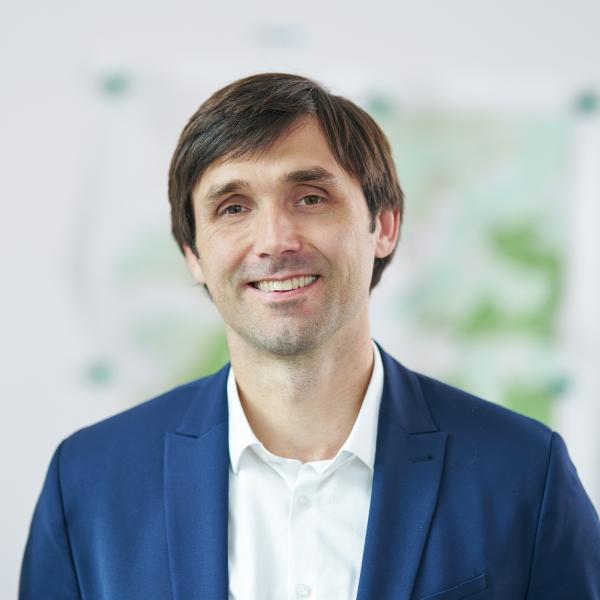 Mann in blauem Anzug steht in einem Raum und lächelt