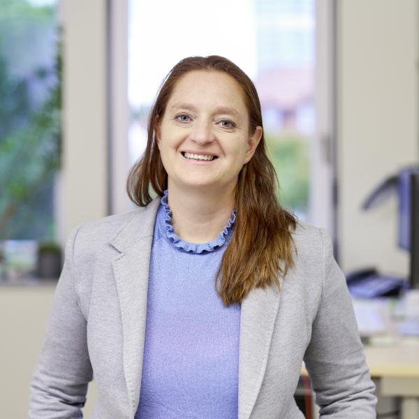 Frau sitzt an einem Tisch und lächelt in die Kamera