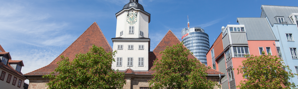 Blick auf das historische Rathaus vom Marktplatz aus, rechts daneben mehrere farbige Gebäude, im Hintergrund der Jentower